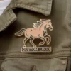 Une épingle à logo de cheval attachée à une veste, présentant un design élégant et des couleurs vibrantes.