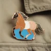 Un élégant pin's de cheval bleu et blanc, apposé sur une veste, qui met en valeur la mode équestre.