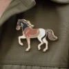 Un pin's de cheval élégant aux couleurs rouge, blanc et noir apposé sur une veste.