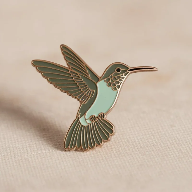 Hummingbird enamel pin displayed on a clean white background, showcasing intricate details and vibrant colors.