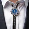 Un hombre exhibe un alfiler de solapa azul y blanco en su camisa, junto con una corbata de bolo del Club de Leones.
