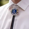 Un hombre muestra un alfiler de solapa azul y blanco, complementado con una corbata de bolo del Club de Leones.