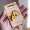 Una mano mostrando un vibrante pin de pizza, destacando un artículo lúdico para los entusiastas de la pizza.