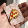 Primer plano de la mano de una persona agarrando un alfiler de pizza, que representa un accesorio estrafalario para los aficionados a la pizza.