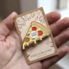 Una mano sosteniendo una tarjeta de bar de pizza adornada con alfileres de pizza de colores.