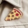 Un caprichoso alfiler de pizza fijado a una chaqueta, que pone de relieve una declaración de moda moderna y única.