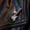 Pin de guitarra punk rock en negro y rojo sujeta a una chaqueta de cuero.