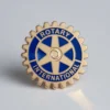 Pin de Rotary International sobre fondo blanco, símbolo de servicio y compromiso con la comunidad.