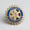 Pin de solapa de Rotary International en dorado y azul, con el nombre de la organización para los socios del club.