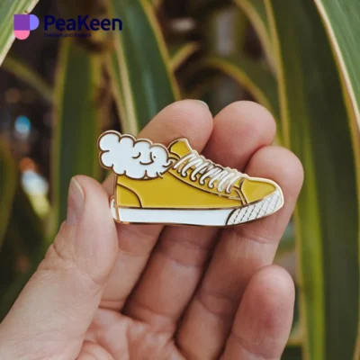 Yellow sneaker enamel pin featuring a whimsical cloud design, perfect for adding flair to any accessory collection