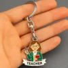 Cartoon woman holding a book on a teacher keychain, symbolizing education and appreciation for teachers.