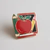 Enamel pin featuring a red apple and pencils, symbolizing appreciation for teachers and education.