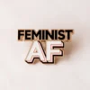 A colorful enamel pin displaying "Feminist AF," symbolizing strong support for feminist movements and equality.