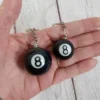 Close-up of a person gripping two black and white billiard balls, part of a billiards keychain.