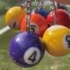 A person holds a bunch of colorful billiard balls, showcasing a billiards-themed keychain in their other hand.