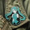 A Miku-themed pin showcasing a girl wearing a green jacket, capturing a lively and colorful aesthetic.