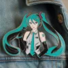 A pin featuring a girl with green hair wearing a blue jacket, inspired by the character Miku.