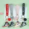 A collection of four PVC Nike keychains, each designed as a sneaker, highlighting unique colors and styles.