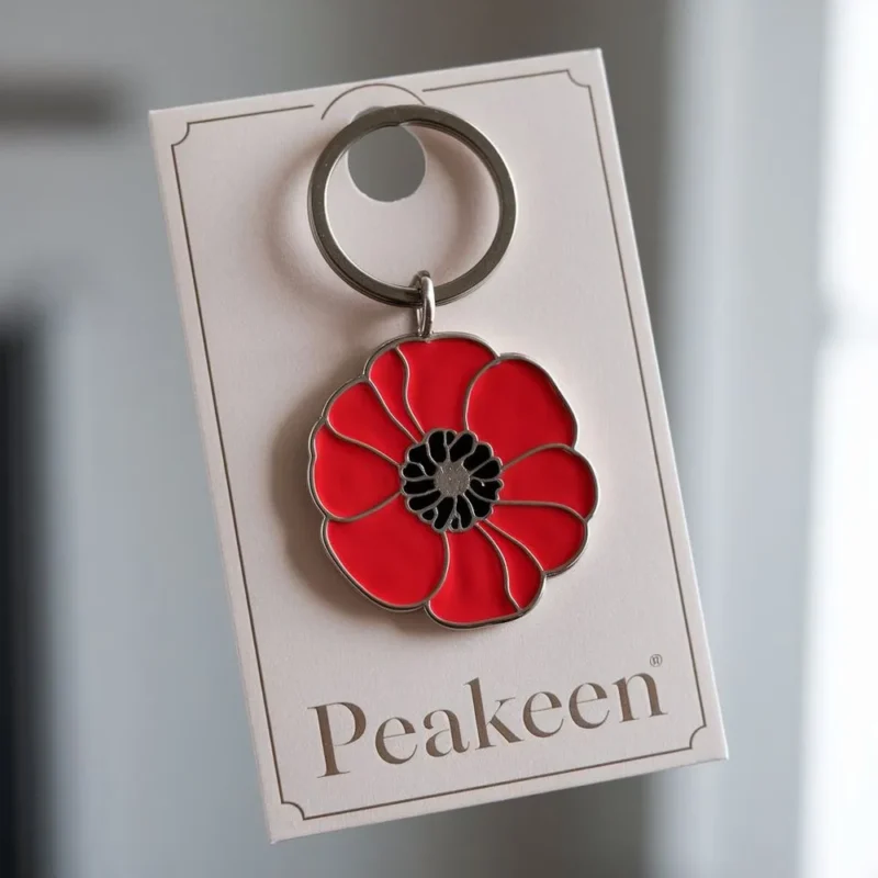 Red enamel poppy keychain with a black and white tag, symbolizing remembrance and honoring veterans.