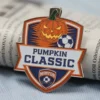 A medal featuring the words "Pumpkin Classic" in bold letters, designed for an enamel soccer medal event.