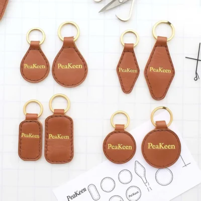 Several embossed leather keychains, each embossed with the word "peakeen," arranged together.
