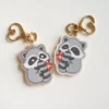 Two small raccoon keychains adorned with heart designs, showcasing a cute and playful accessory.