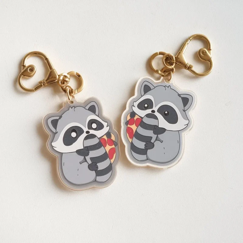 Two small raccoon keychains adorned with heart designs, showcasing a cute and playful accessory.