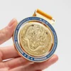 A person proudly holds a gold medal featuring a dragon, part of a spinning medal collection.