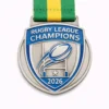 A silver and blue Rugby League Champions medal for 2026, featuring a stylized rugby ball flying through goalposts, a star beneath the posts, and a green and yellow ribbon attached at the top.
