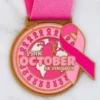Pink October gold medal representing breast cancer awareness and support for survivors and fighters.