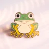 Smiley-faced frog enamel pin with vibrant green color and glossy finish, perfect for adding charm to accessories.