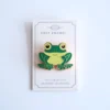Colorful enamel pin of a frog, showcasing vibrant green hues and charming design elements.