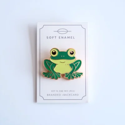 Colorful enamel pin of a frog, showcasing vibrant green hues and charming design elements.