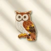 Brown and white owl enamel pin featuring detailed feathers and a cute expression, perfect for accessories or collectibles.