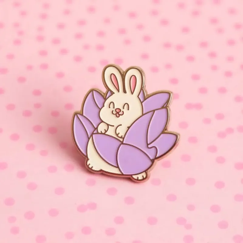 A cute bunny sitting on a purple flower, featured on a colorful rabbit enamel pin.