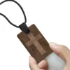 A hand holding a wooden cross on a keychain, which serves as an NFC Bible necklace for quick scripture access.