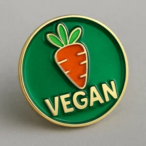 Enamel pin in green and gold displaying the word "vegan," serving as a badge for promoting veganism.