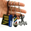 A hand displays a keychain with miniature barber shop items, such as scissors and a comb, highlighting barber culture.