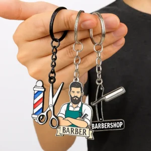 Close-up of a person gripping a keychain adorned with small barber tools, including scissors and a comb.