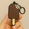 A close-up of a person holding a fun keychain shaped like a popsicle, featuring bright colors and a playful design.