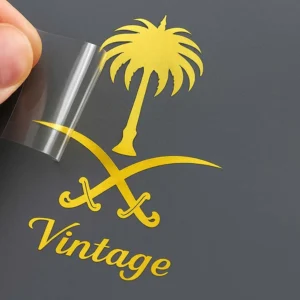 A hand displays a paper with "vintage" written on it, accompanied by a metal sticker for a phone, highlighting a nostalgic theme.