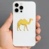Close-up of a person displaying a white iPhone case adorned with a gold camel metal sticker.