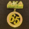 Gold and pink pin featuring the words "akka pearl son," part of the aka pins collection.