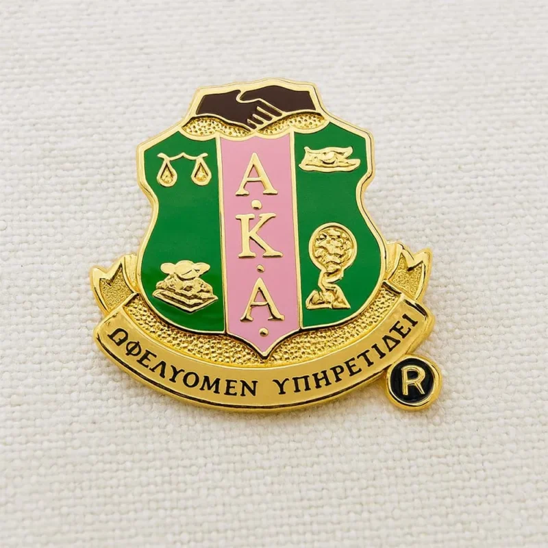 Alpha Kappa Phi pin badge, also known as an AKA pin, featuring the organization's emblem in gold and purple.