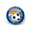 Pin badge featuring the Ocean City FC logo, representing the football club's identity and spirit.