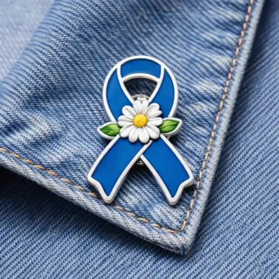 Blue awareness ribbon enamel pin featuring a white daisy flower, displayed on a denim jacket to symbolize hope, remembrance, and support for awareness causes.