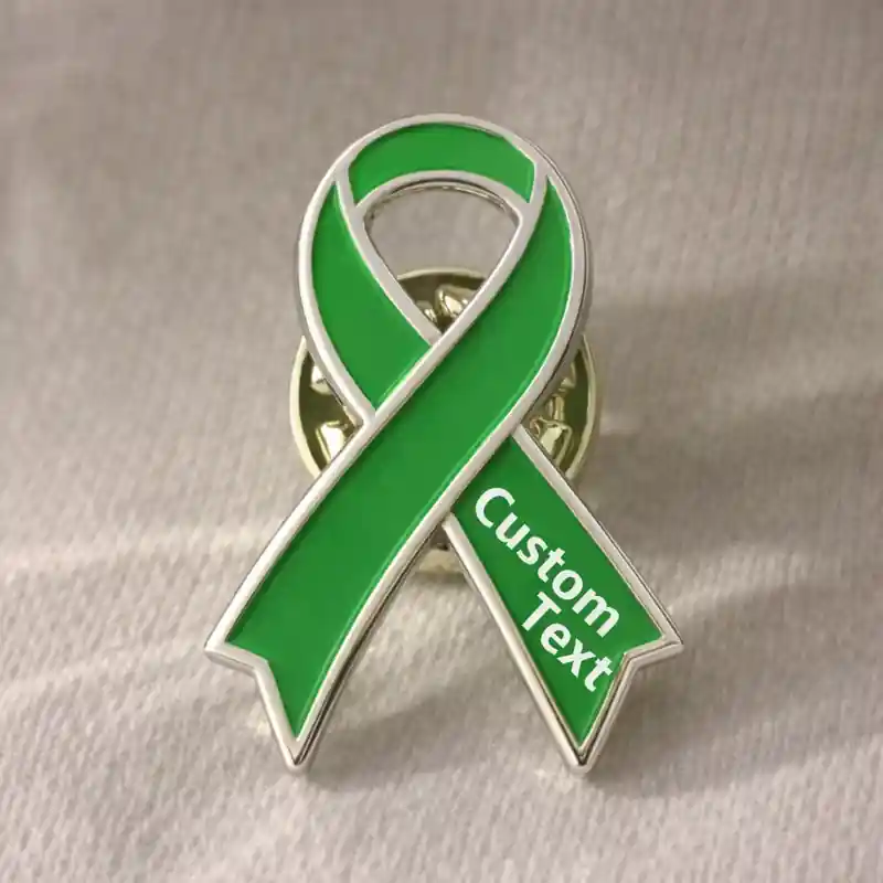 Close-up of a green awareness ribbon enamel pin with silver outline and custom text, symbolizing awareness and support for health and social causes.