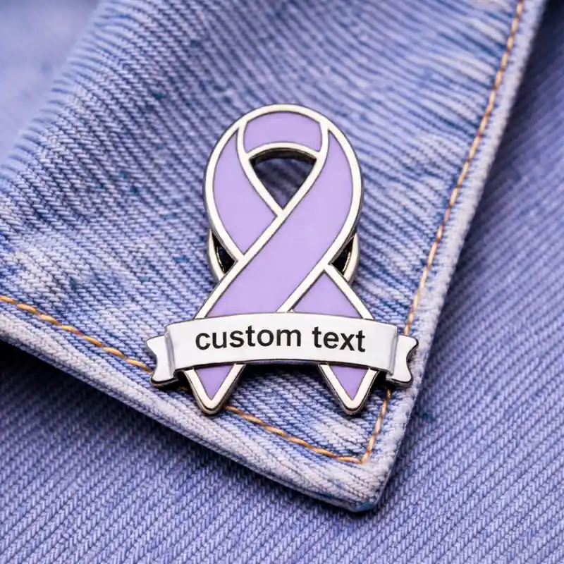 A purple enamel ribbon pin with a customizable "custom text" banner, pinned to denim fabric.