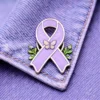 A lavender enamel ribbon pin featuring a butterfly and green floral accents, attached to a denim jacket.