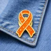 Orange awareness ribbon enamel pin with stars design, displayed on denim fabric, symbolizing support for fire-related causes or awareness campaigns.